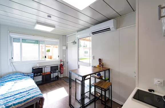 ue depuis l’entrée d’un studio modulaire ALGECO® tout équipé avec lit, table repas, climatisation et grande fenêtre à Villenave-d’Ornon