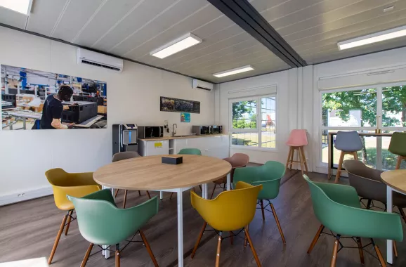 Espace café convivial dans la cafétéria modulaire ALGECO® temporaire de L-Acoustics avec vue sur l’extérieur