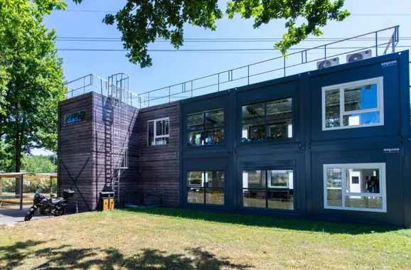 Vue d’ensemble du bâtiment modulaire ALGECO® temporaire de L-Acoustics en R+1 avec bardage bois et parking deux-roues