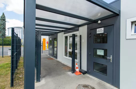 Vue rapprochée de l’entrée du poste de garde modulaire ALGECO® du site Tereos avec auvent et porte vitrée