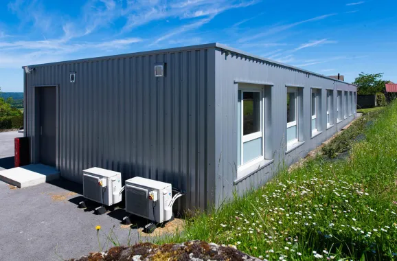 Bâtiment scolaire modulaire ALGECO® ENILEA avec bardage gris et équipements techniques