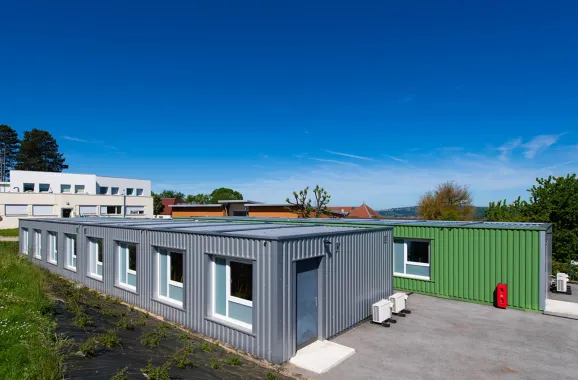Vue extérieure des salles de classe modulaires ALGECO® ENILEA avec bardage gris et vert