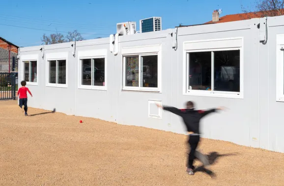 Bâtiment scolaire modulaire ALGECO® blanc avec enfants dans la cour de l’école de Marsat