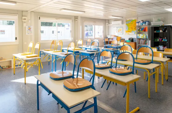 Salle de classe modulaire ALGECO® lumineuse avec chaises posées sur les tables