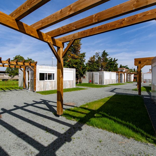 Allée paysagère au sein du village modulaire ALGECO® avec pergolas bois et studios indépendants pour demandeurs d’asile à Villenave-d’Ornon