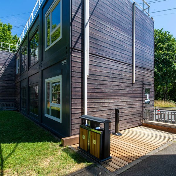  Façade extérieure en bardage bois de la cafétéria modulaire ALGECO® temporaire de L-Acoustics dans un environnement arboré