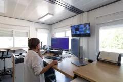 bureau modulaire moderne ALGECO® avec une personne travaillant à son poste de travail et vidéosurveillance.