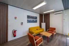Salle de pause d’entreprise modulaire ALGECO® avec canapé jaune et fauteuils orange